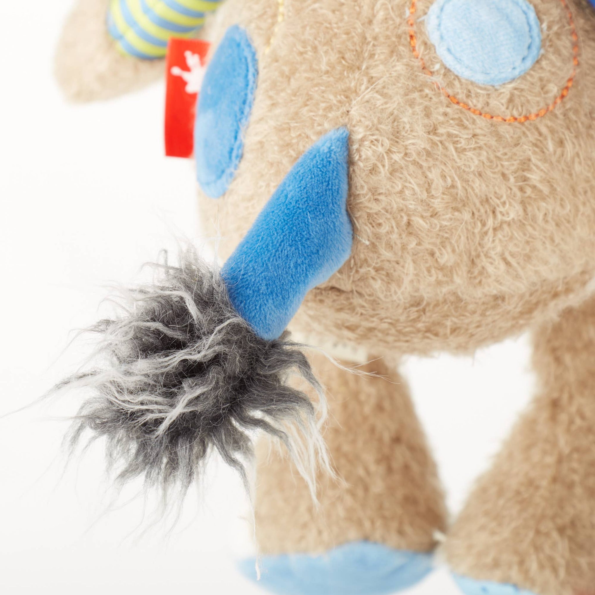 Close-up of a plush toy with blue accents and a tag on a white background