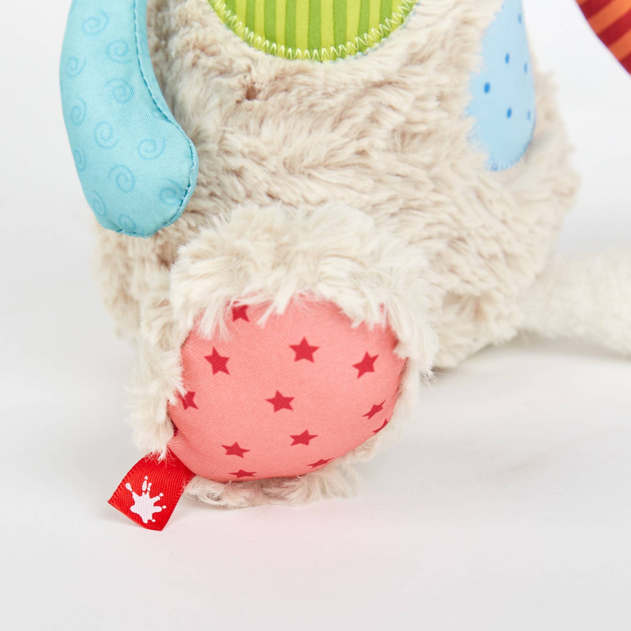 Close-up of a plush toy with a pink bottom featuring star patterns on a white background