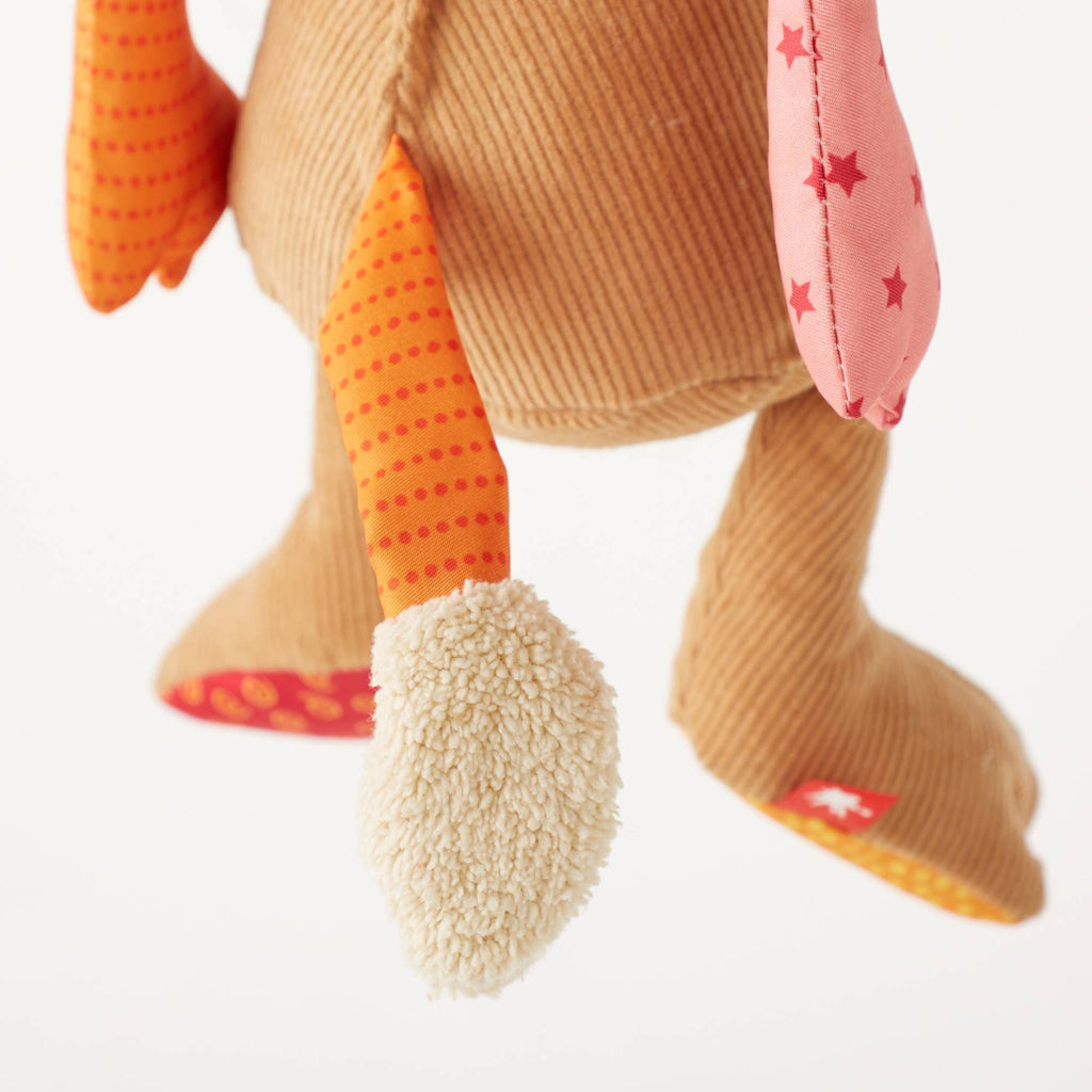 Close-up of a plush toy with orange and pink accents on a white background