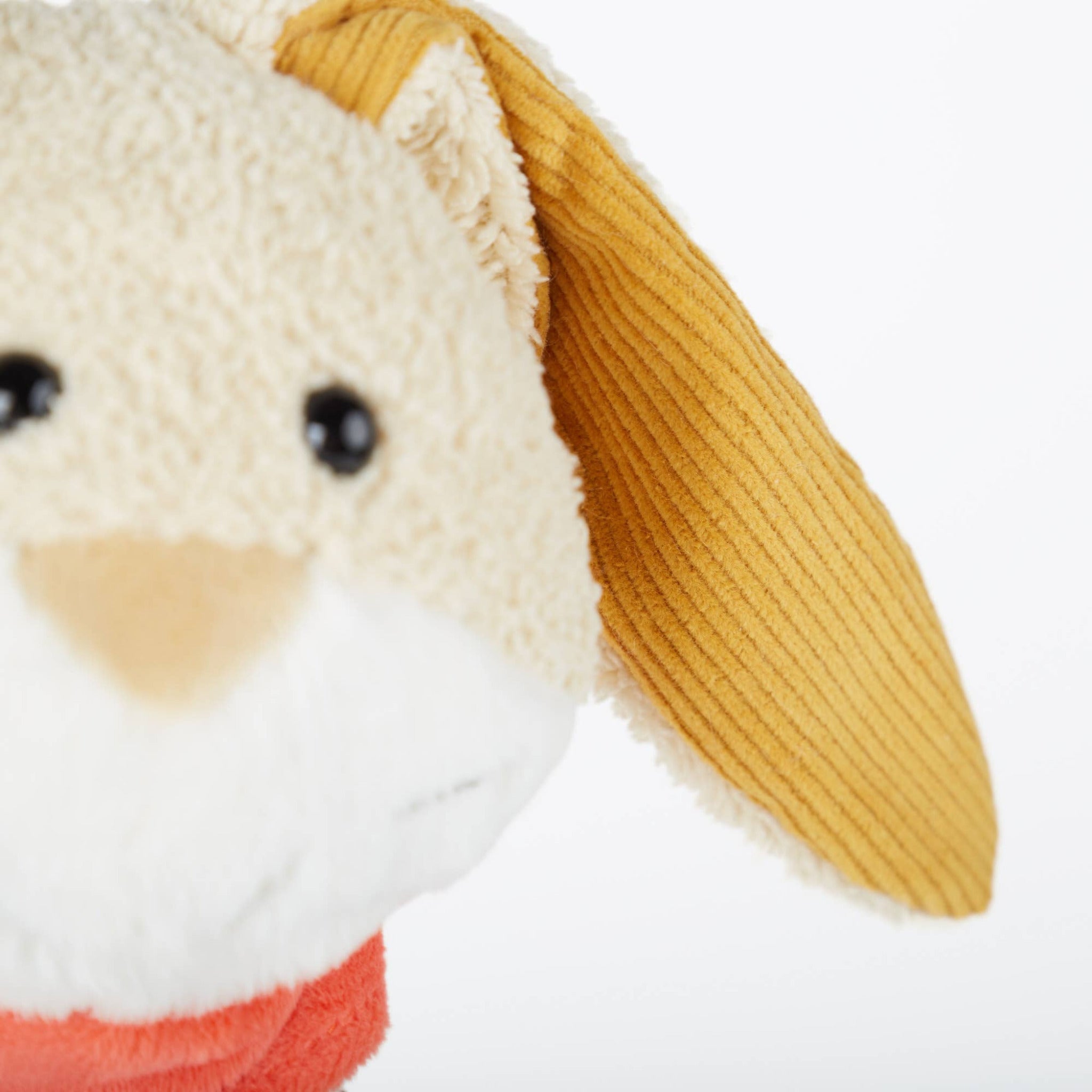Close-up of a plush toy with a yellow ear on a white background