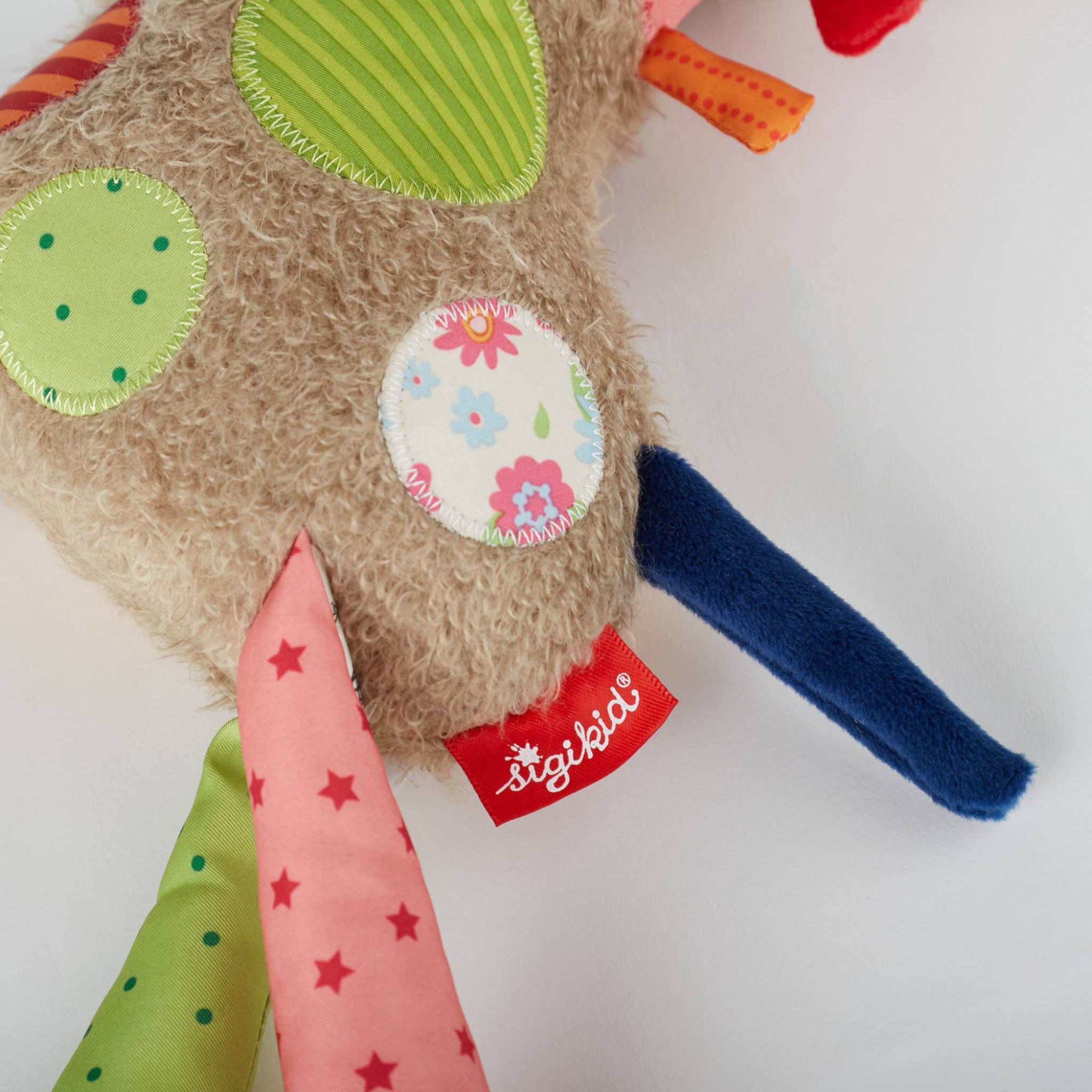 Colorful children's toy with floral patch and colorful fabric elements on a white background