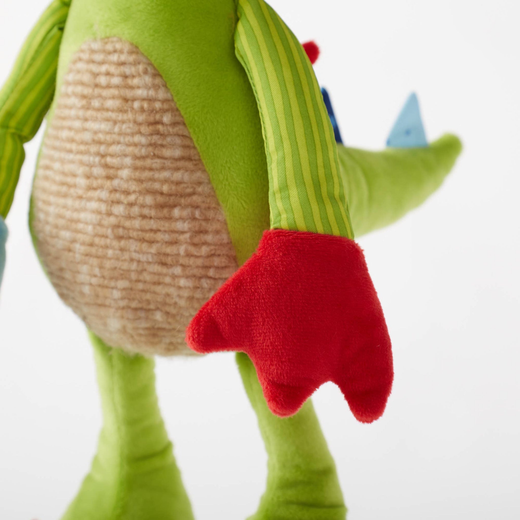 Close-up of a green dinosaur toy with red feet on a white background