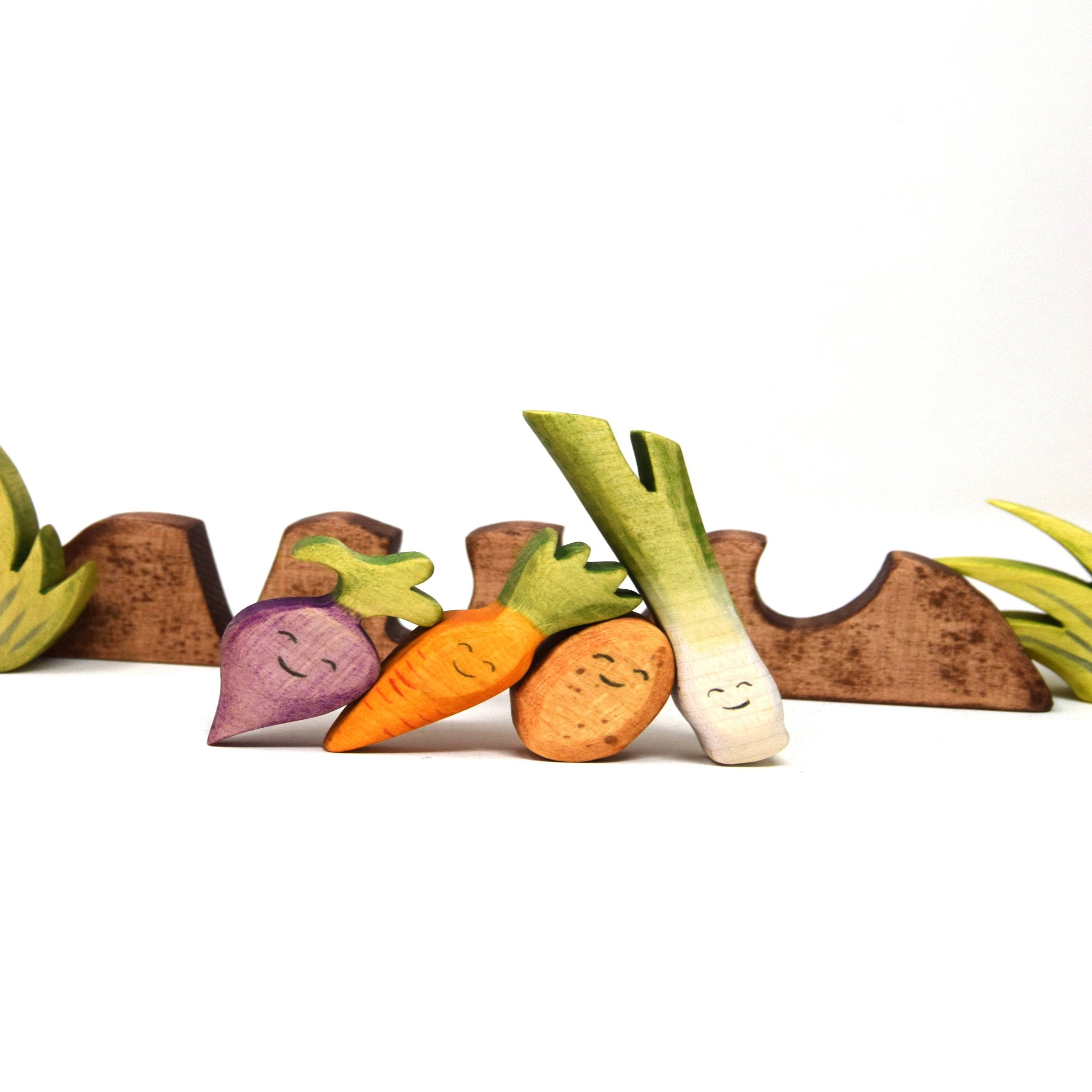 Colorful toy vegetables including a carrot, radish, and leek on a white background