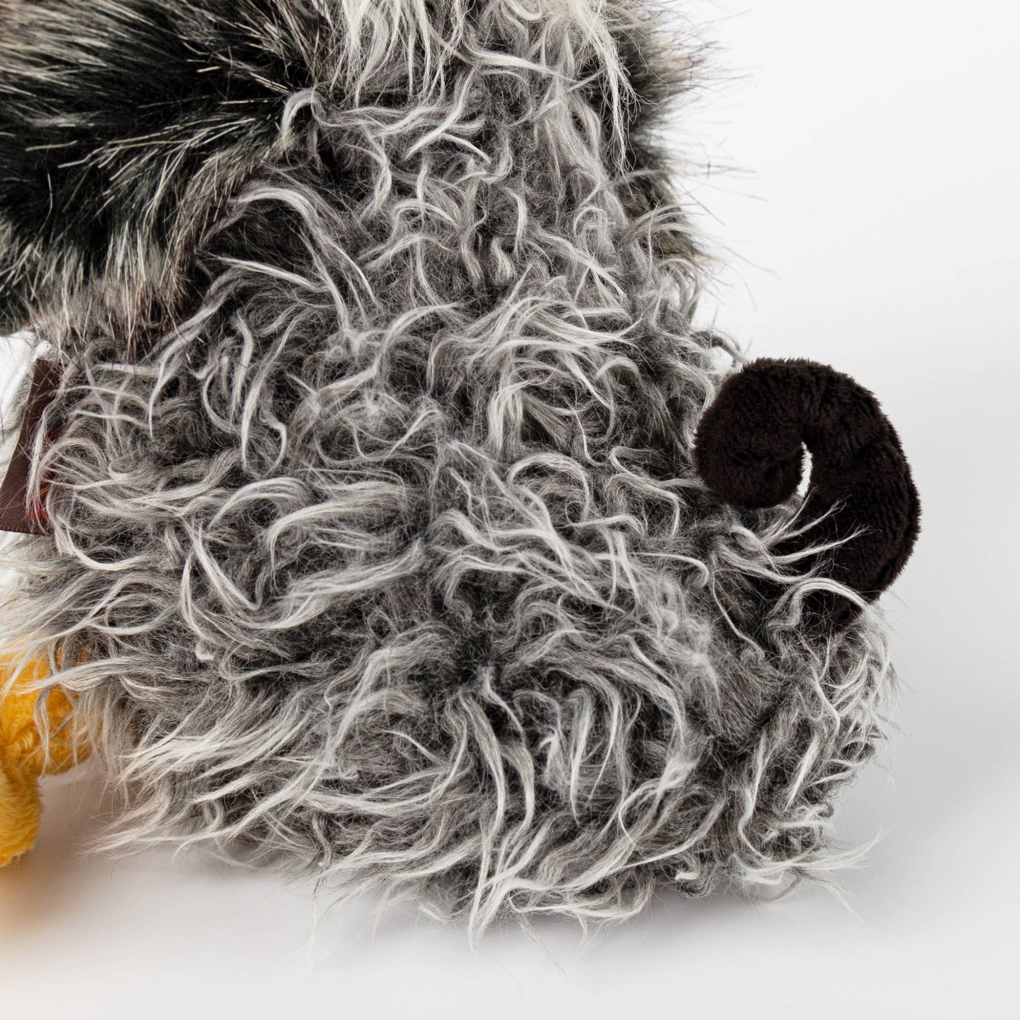 Close-up of a plush toy with a gray beard and black hat on a white background