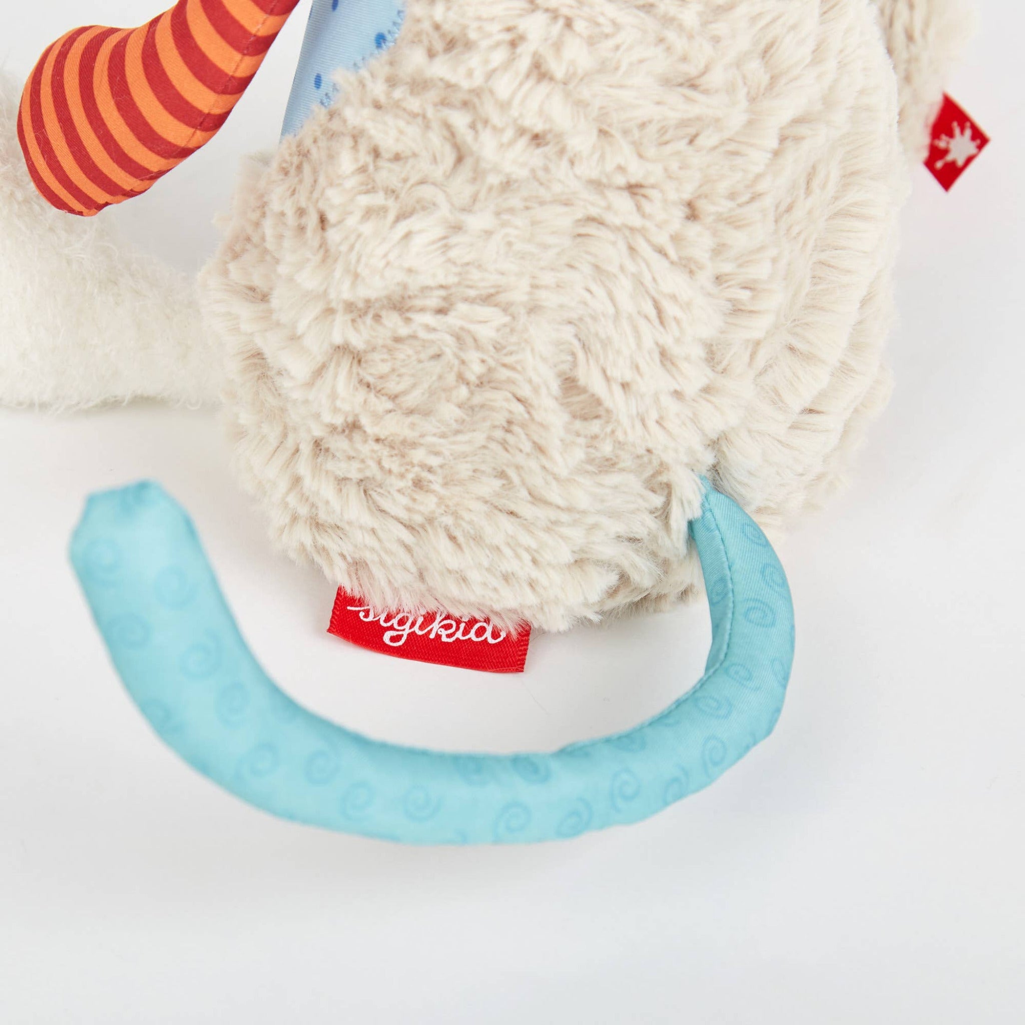 Close-up of a plush toy with a textured ball and blue arch, featuring a visible brand label.