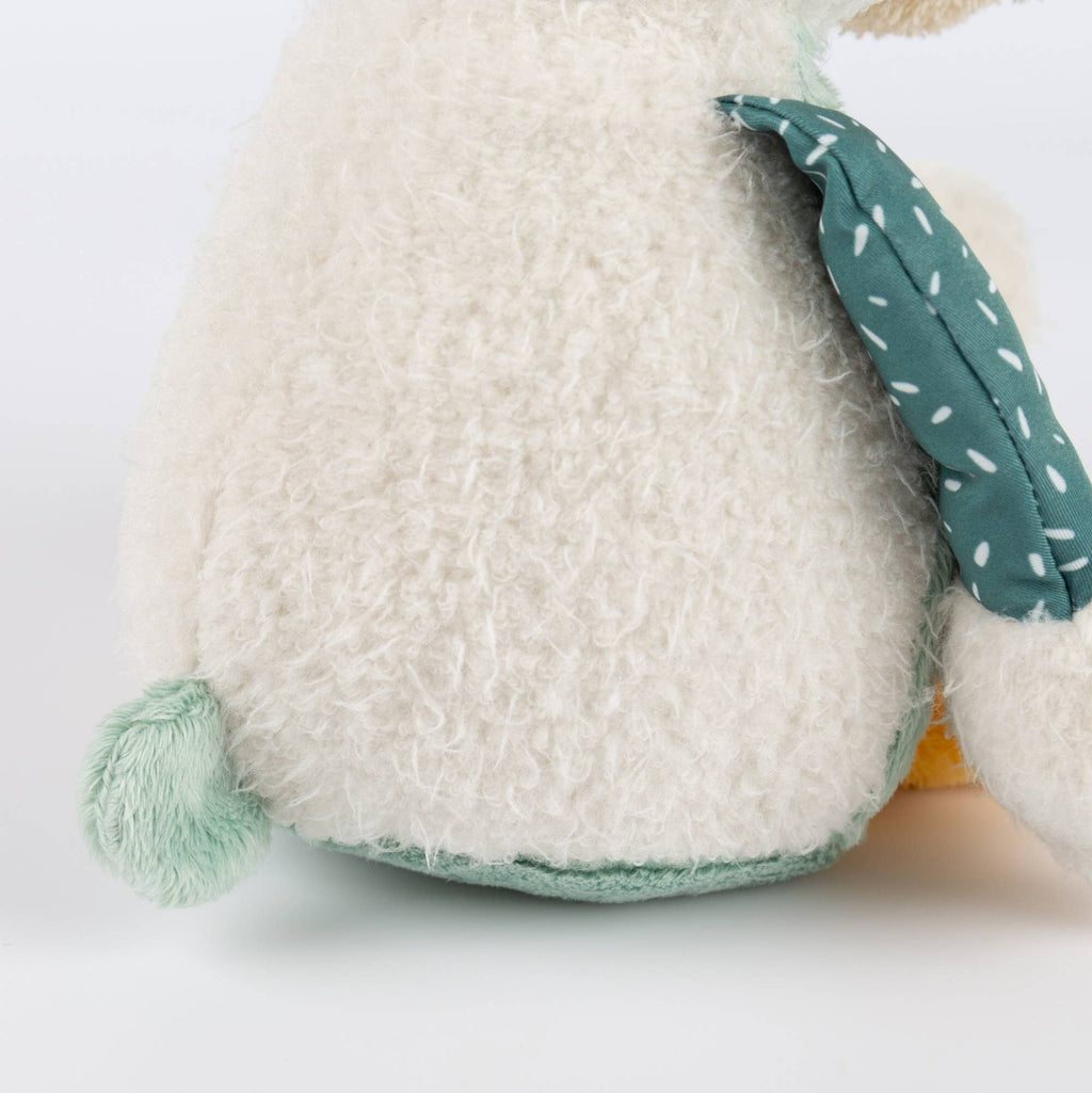 Close-up of a plush toy with a textured white body and green ears on a light gray background