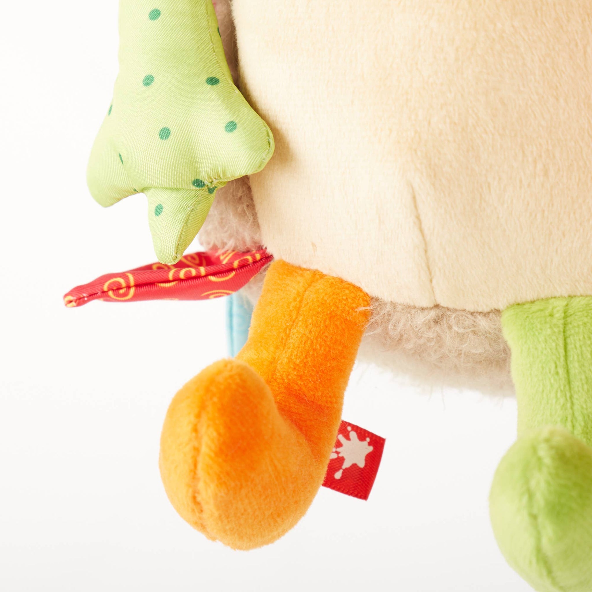 Close-up of a plush turtle toy with a red tag on a white background