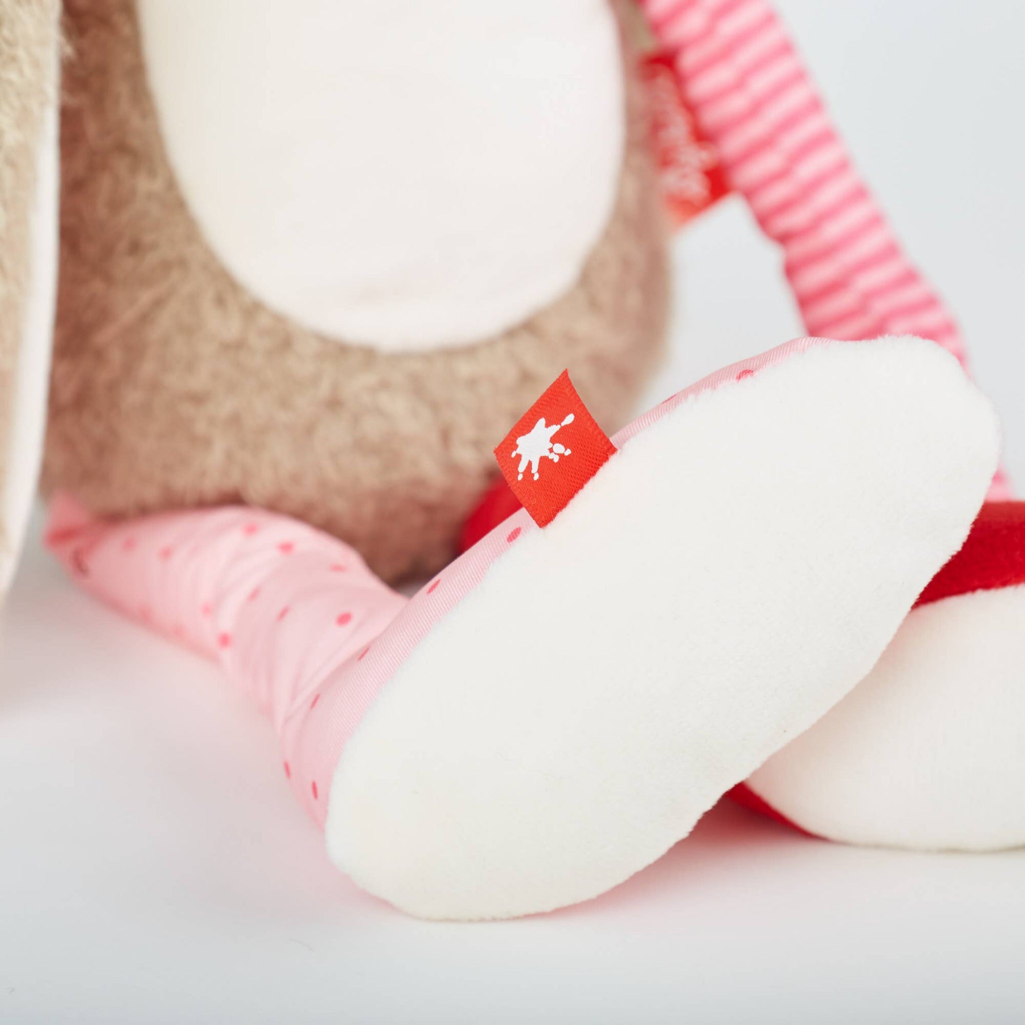 Close-up of a plush toy with a red flag featuring a white silhouette on a light background