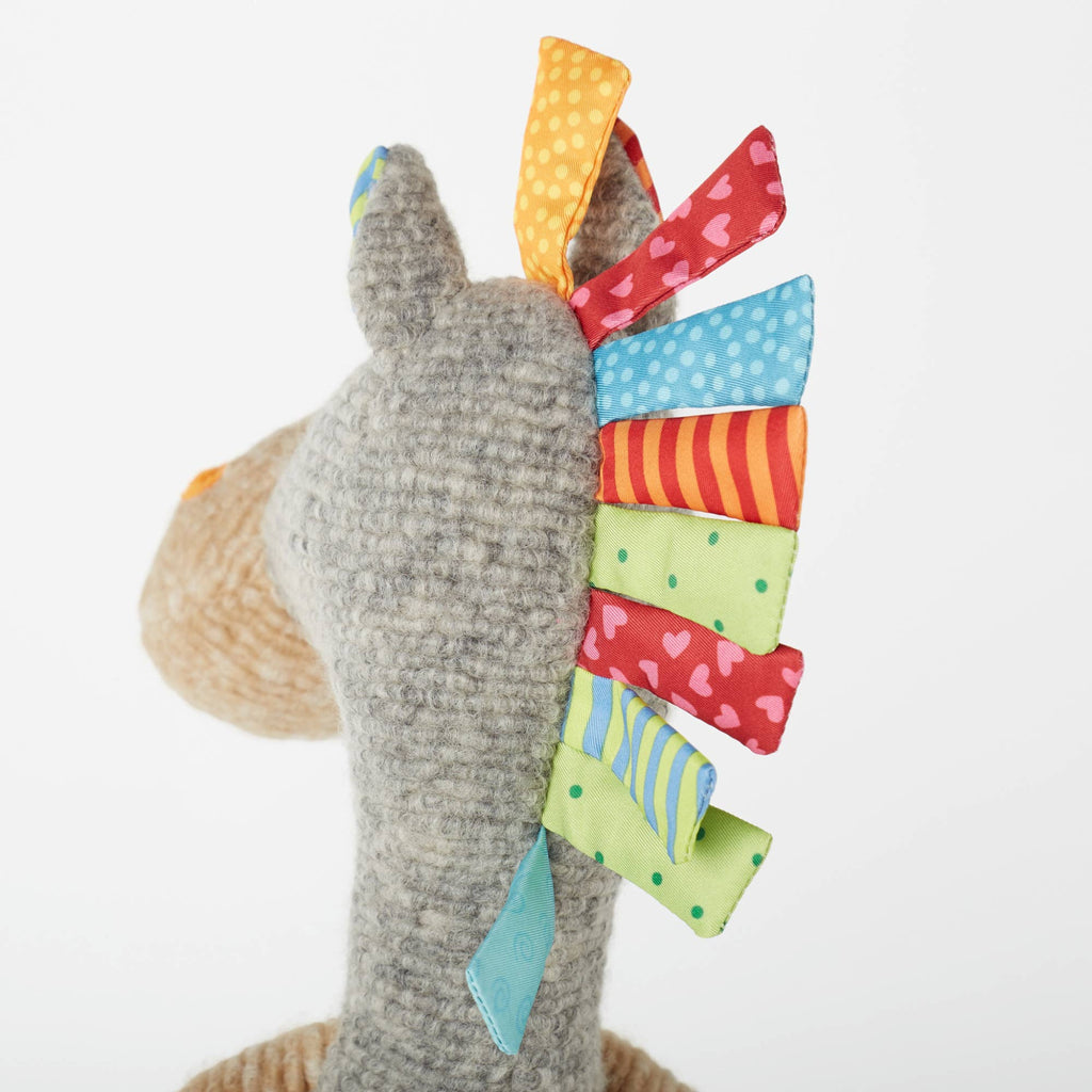 Plush toy with colorful fabric tail on a white background