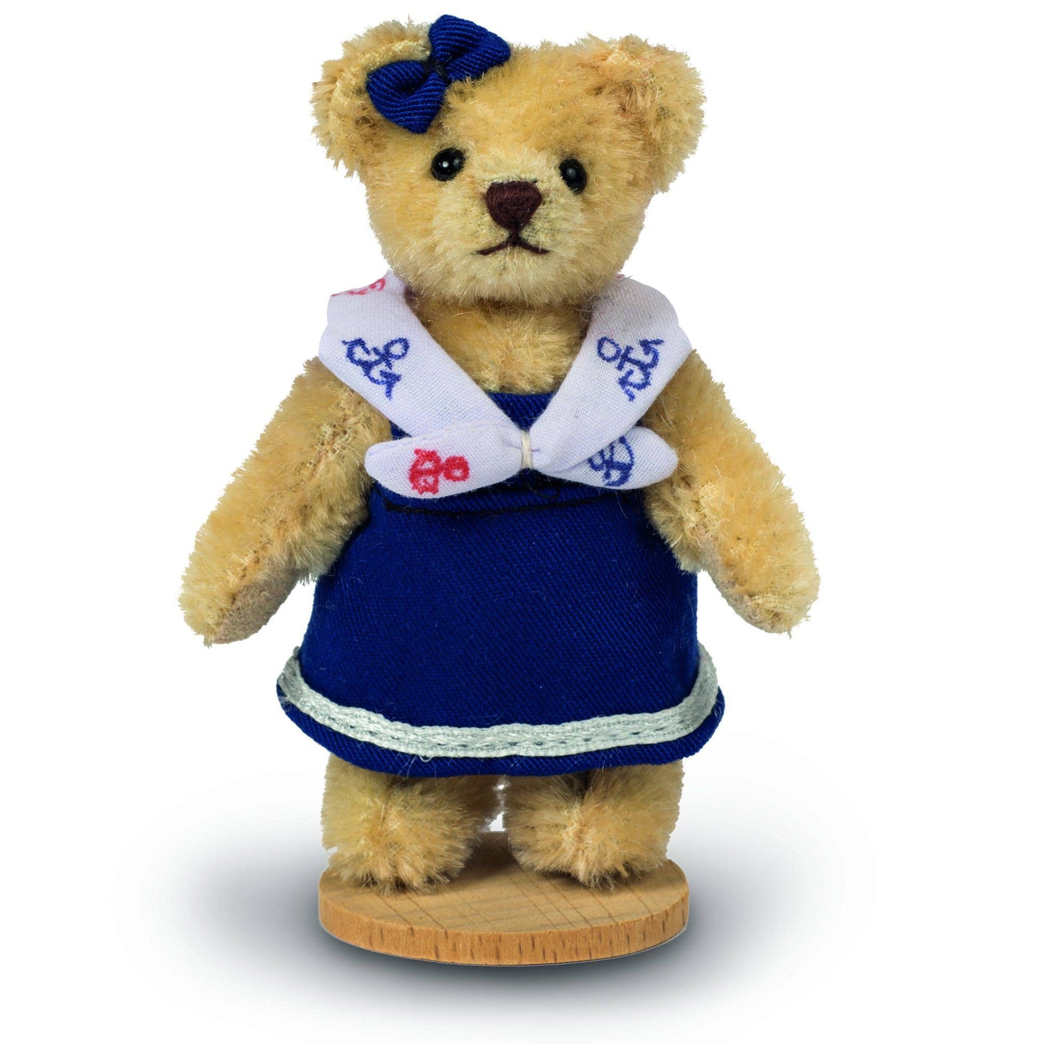 Teddy bear in a blue dress with a white collar on a white background