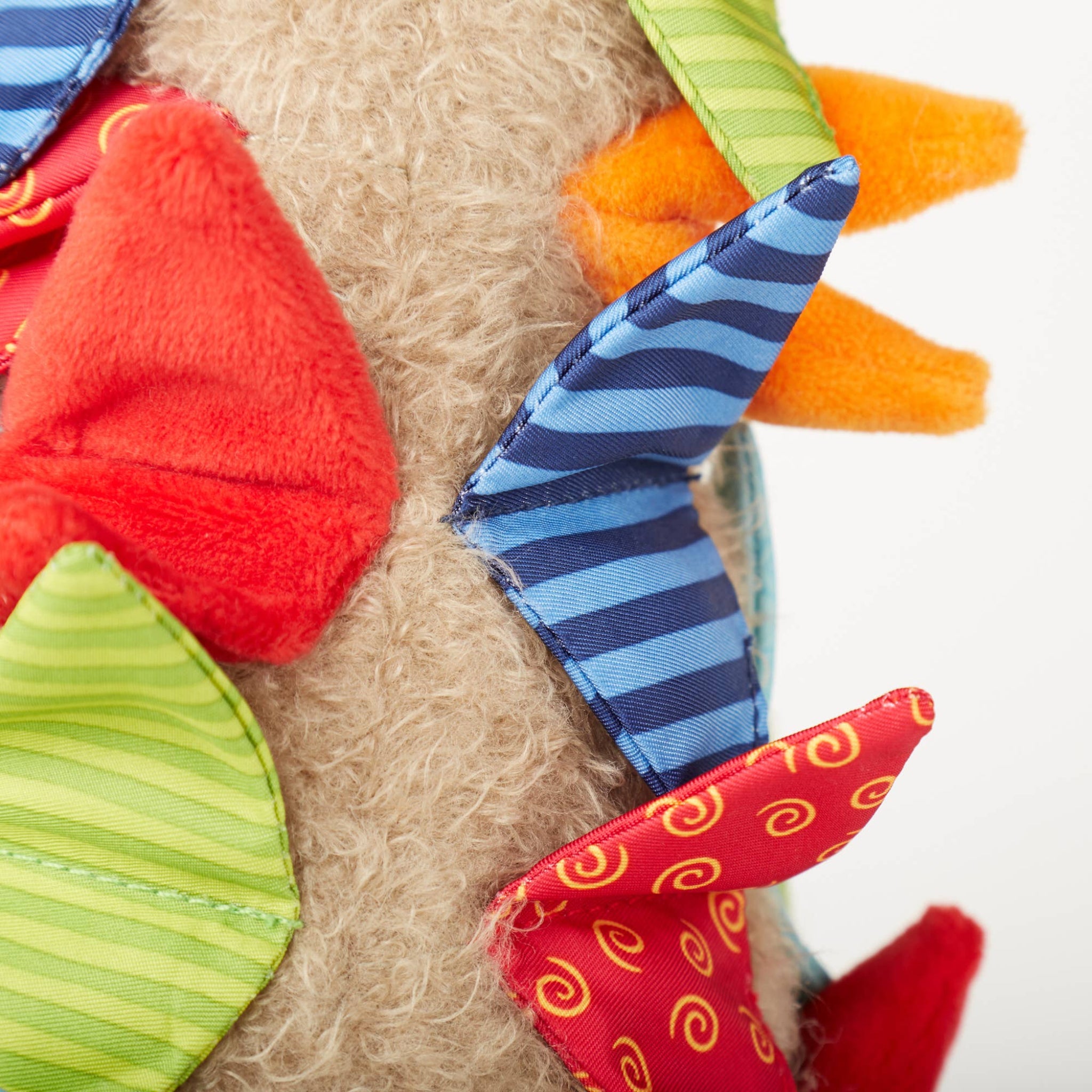 Close-up of a soft toy with colorful fabric pieces on a neutral background