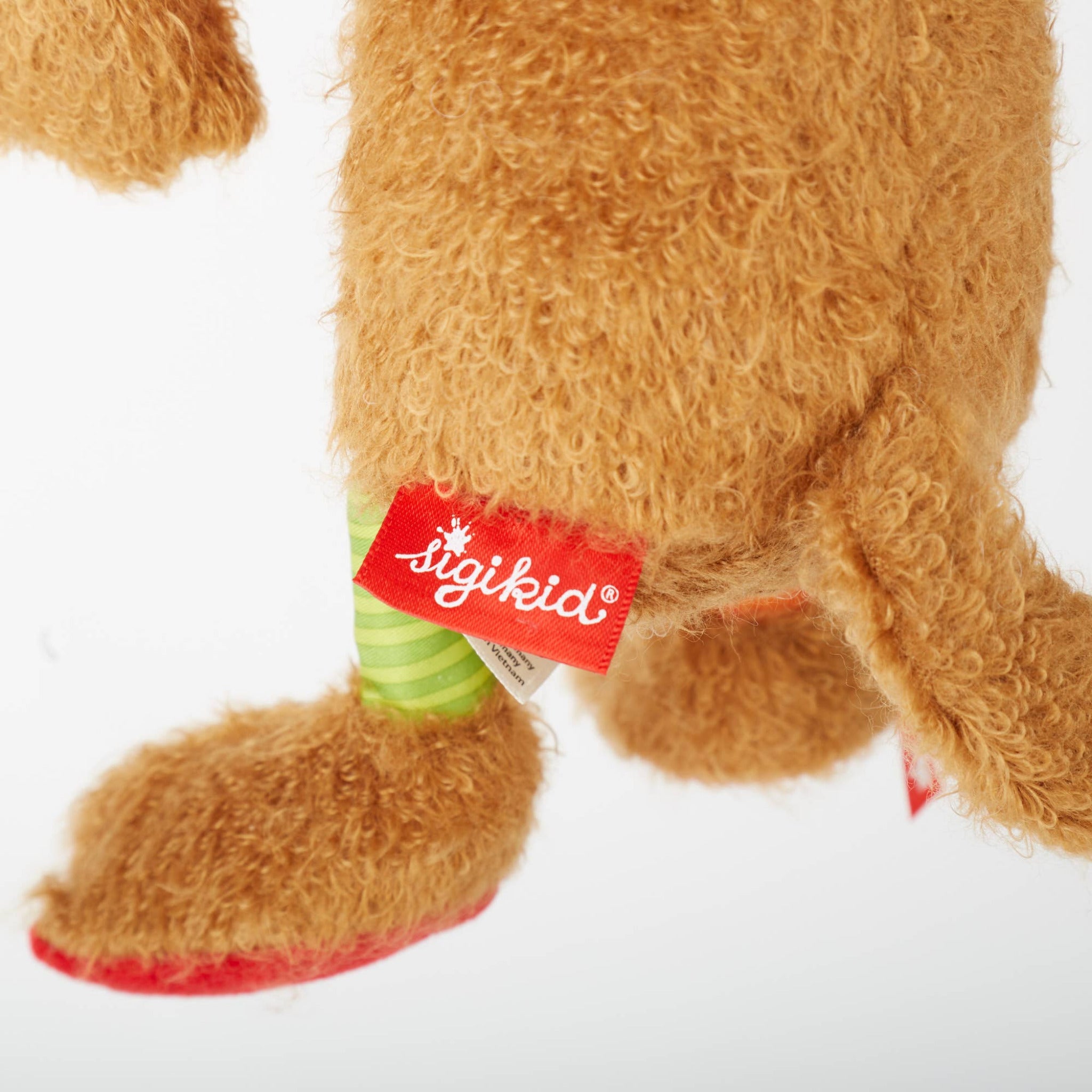 Close-up of a brown plush toy with a red 'sigikid' tag on a white background