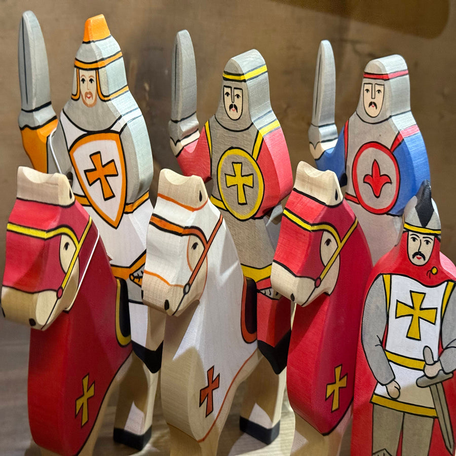 Wooden toy knights with colorful armor and shields on a wooden surface
