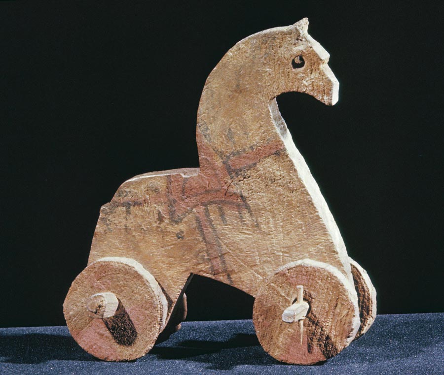 Wooden toy horse with wheels on a dark background
