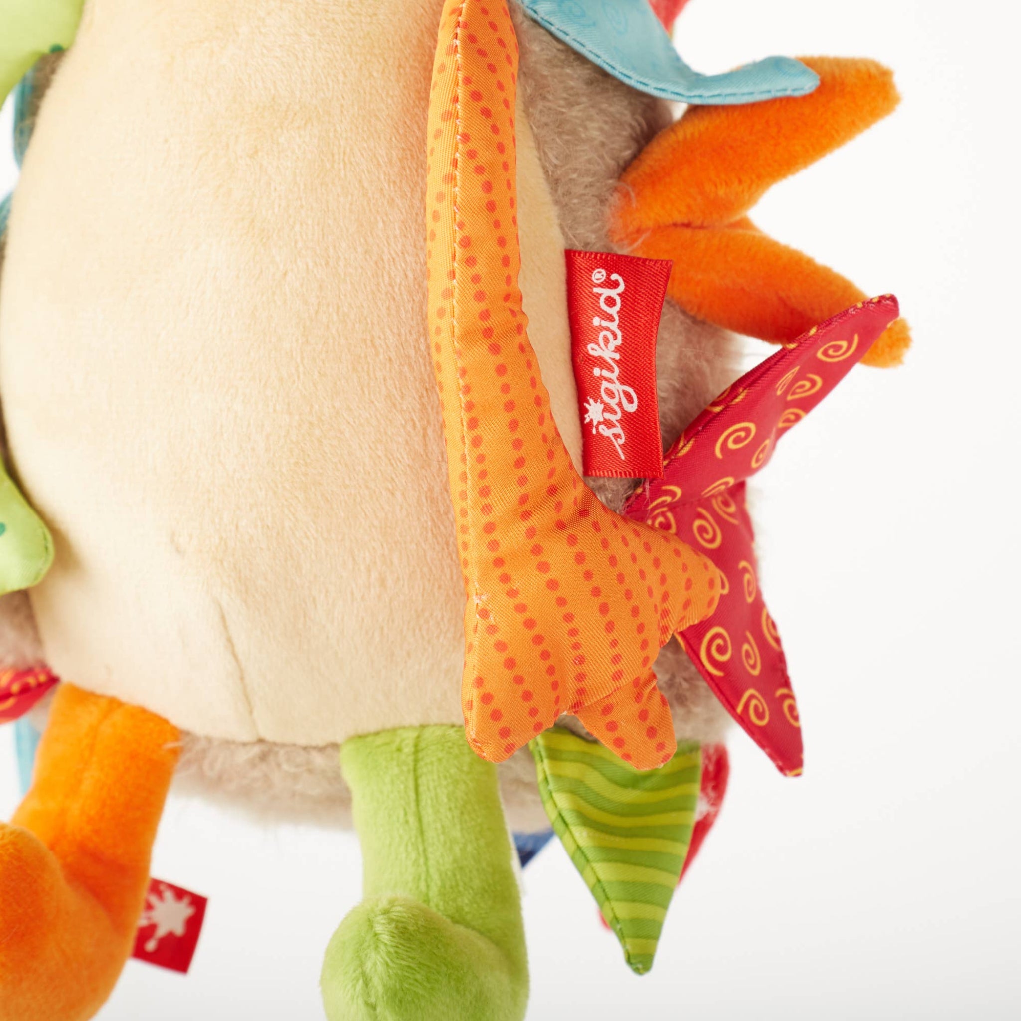 Close-up of a colorful plush toy with a brand tag on a white background