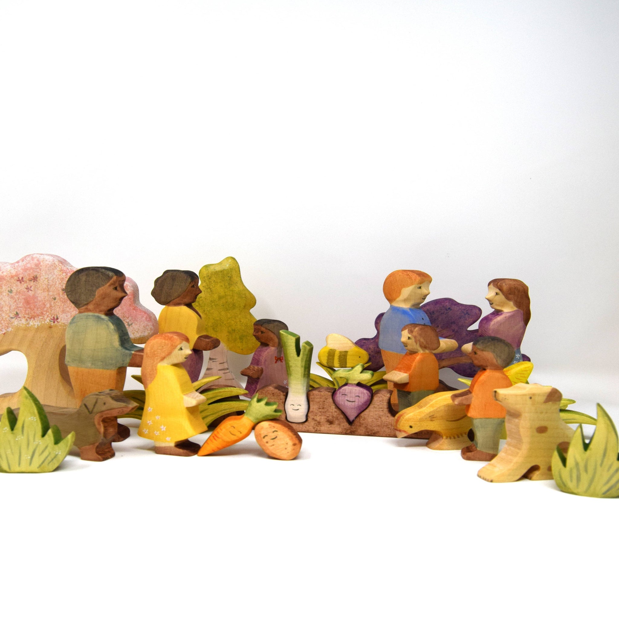 Colorful wooden figurines of people and vegetables on a white background