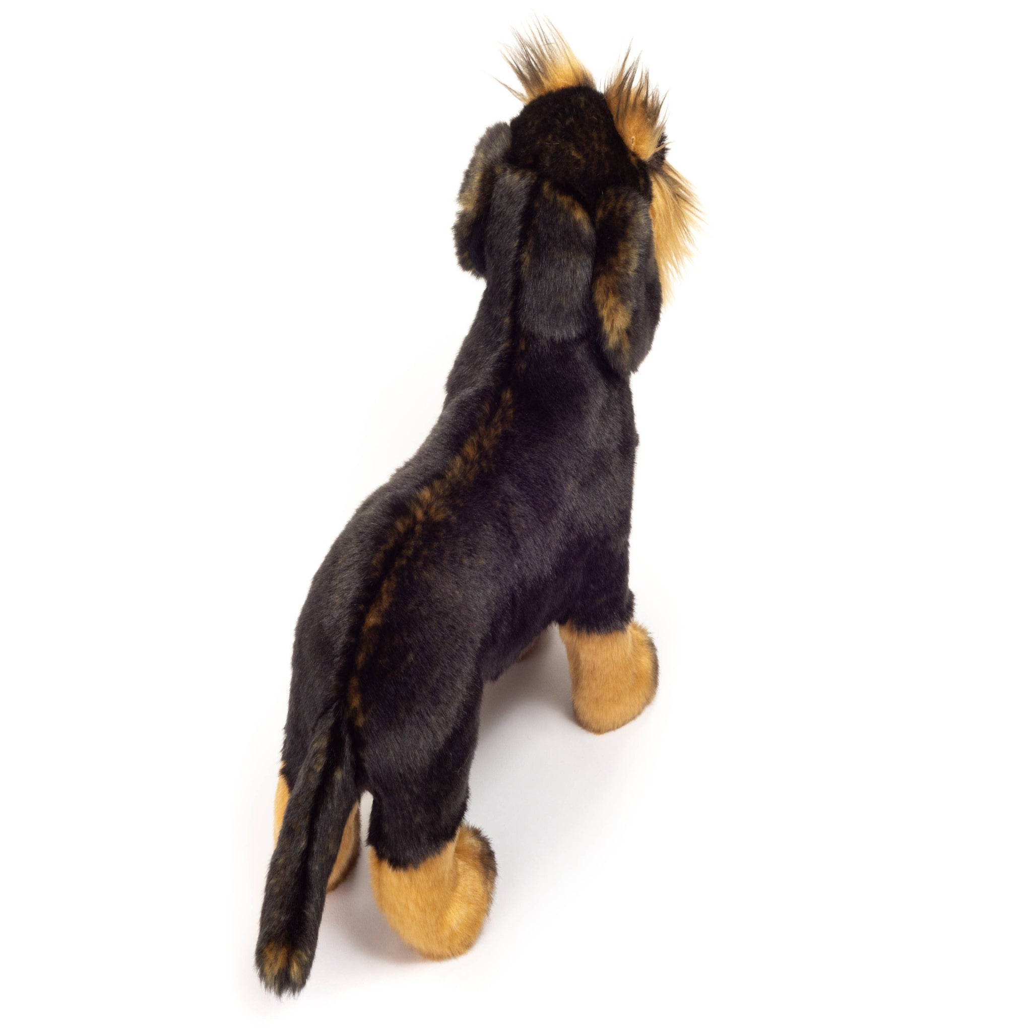 Plush toy resembling a dog with black and brown fur on a white background