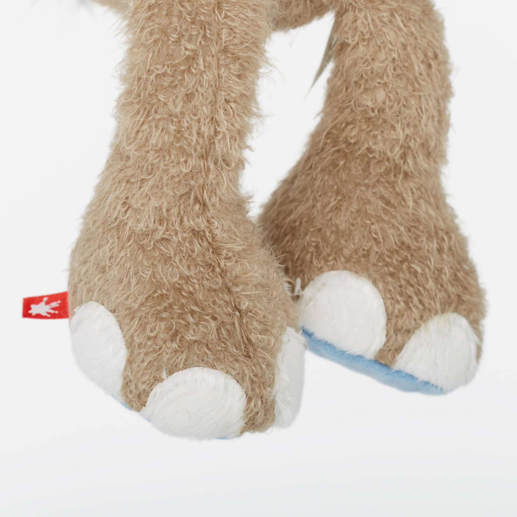 Close-up of plush toy legs with white paws on a light gray background