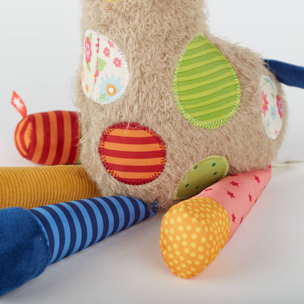 Colorful plush toy with various patches on a white background