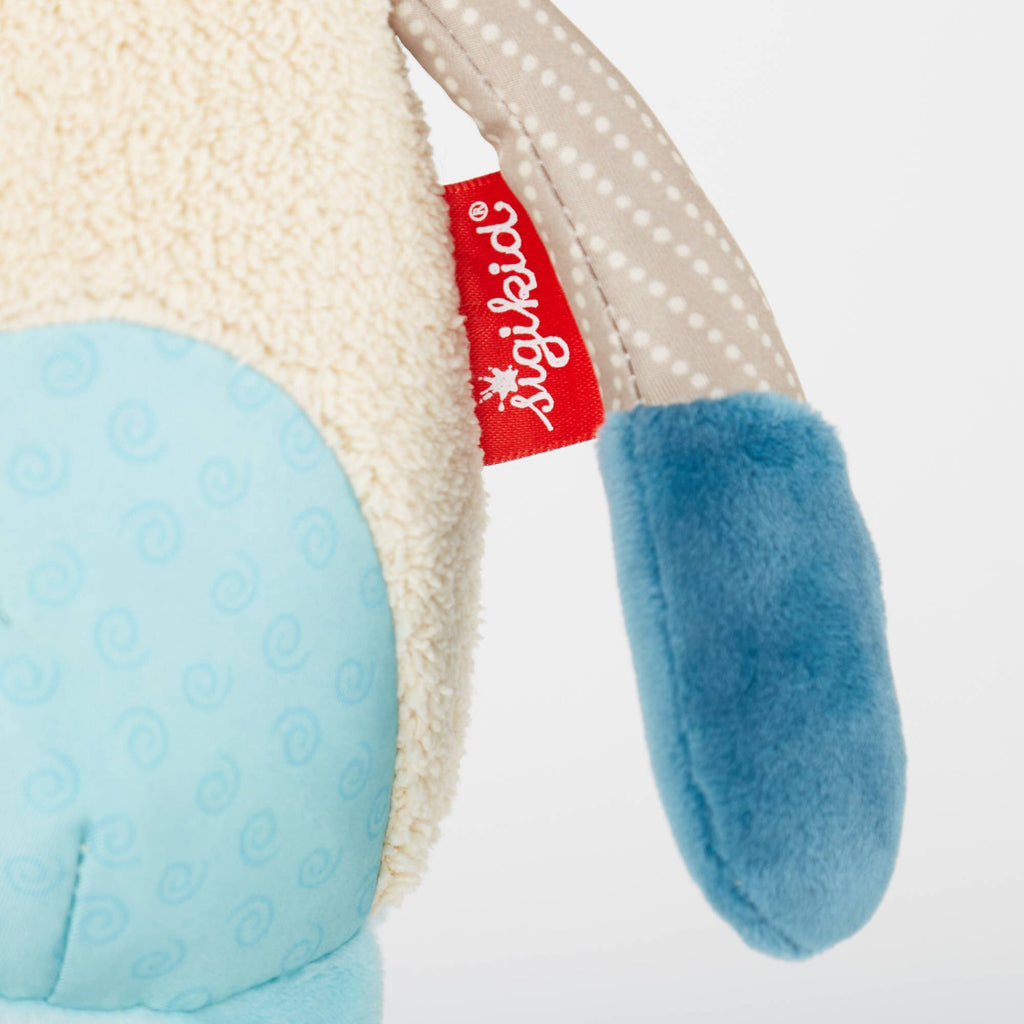 Close-up of a soft toy with blue accents and a visible Sigikid tag on a white background