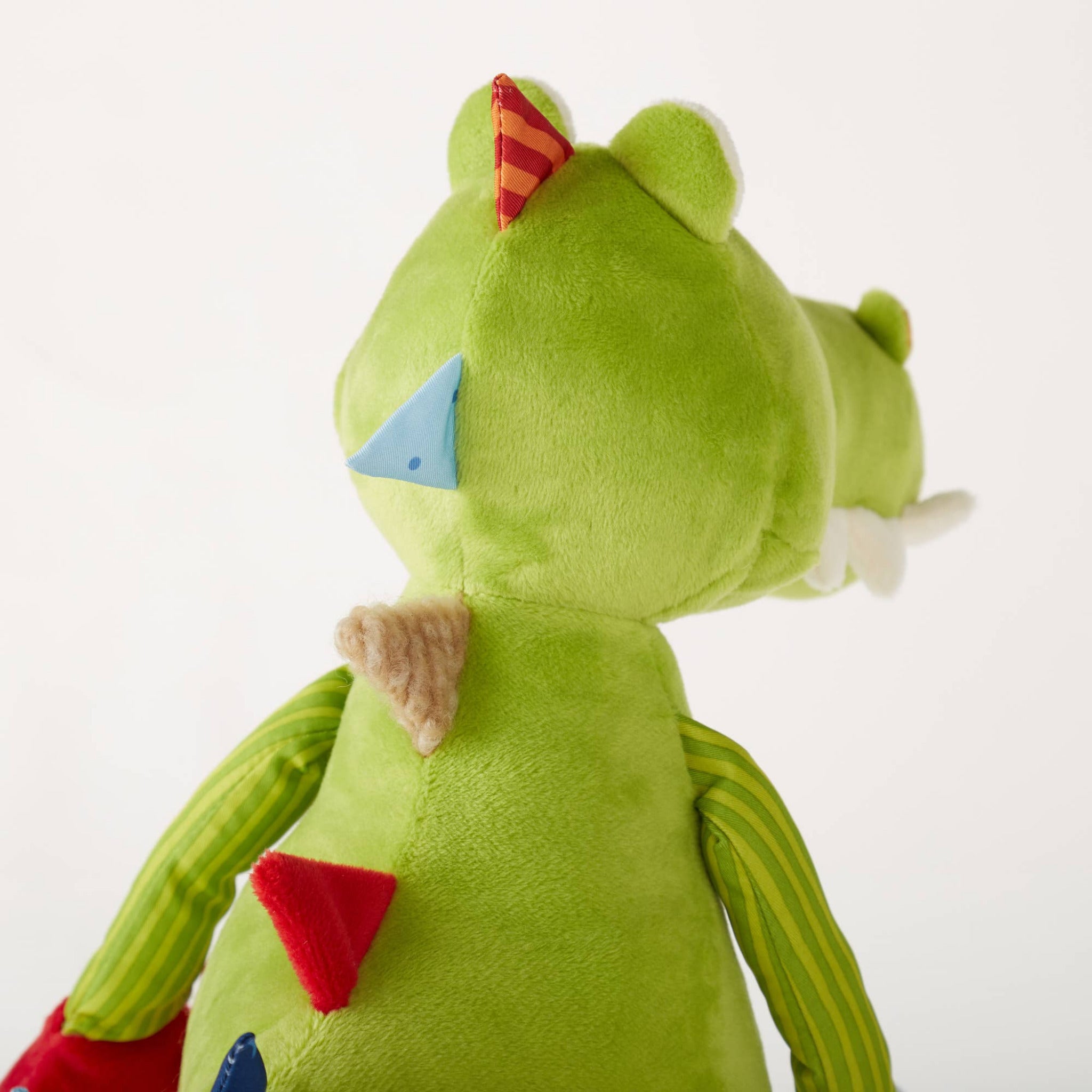 Green plush toy with colorful accents on a white background