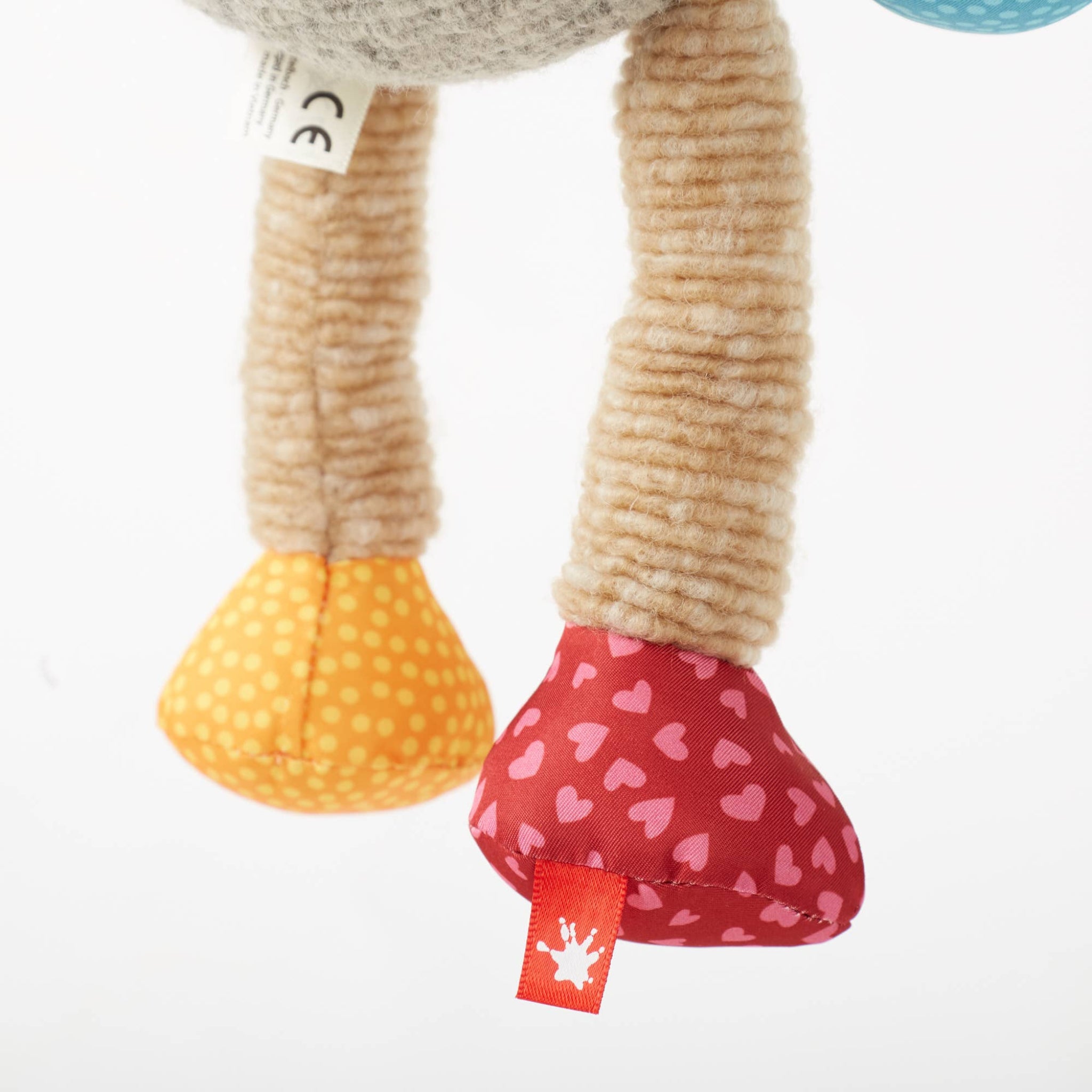 Close-up of a plush toy with colorful feet on a white background